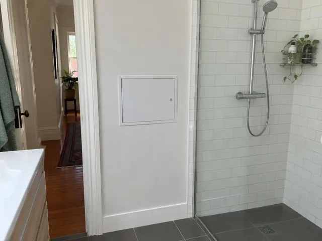 Neat access panel in a painted bathroom wall beside a tiled shower in Annandale